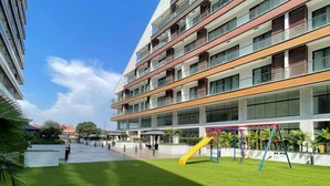 Un edificio moderno con varios balcones y una zona de juegos con un tobogán.