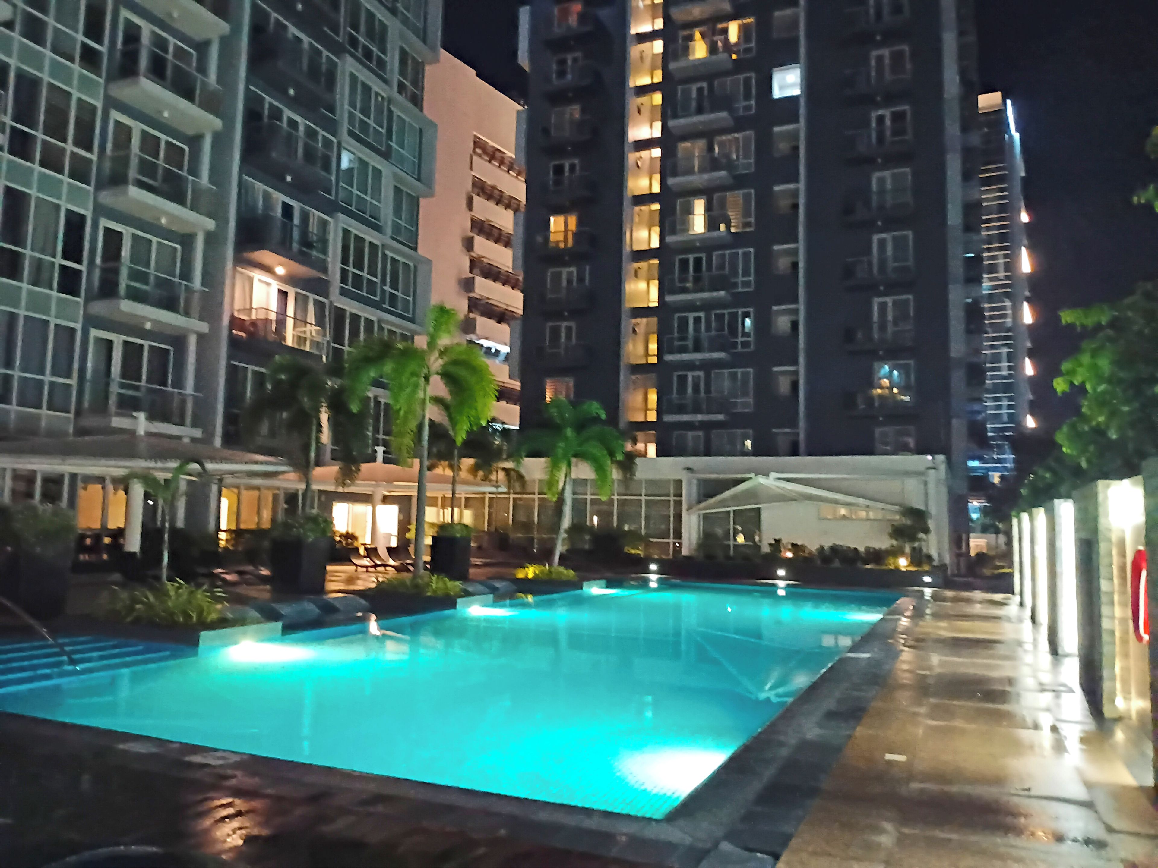 A swimming pool with a covered area, surrounded by high-rise buildings with illuminated windows.