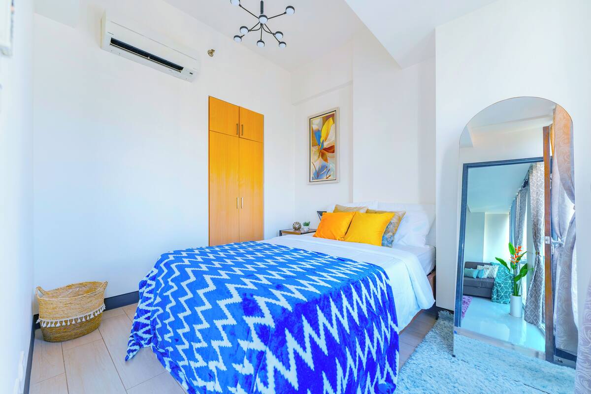 A bedroom with a bed, a wardrobe, a mirror, and a view into another room.