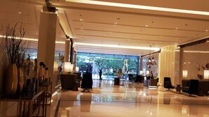 A spacious lobby with a polished floor, modern furniture, and large windows offering a view of the outdoors. - One Pacific Residence 1BR Ocean View (Lapu-Lapu)