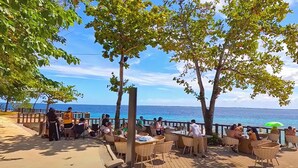 An outdoor dining area with tables and chairs, overlooking the ocean. - One Pacific Residence 1BR Ocean View (Lapu-Lapu)