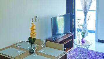 A dining area with a table set for four, a television, and a purple rug.