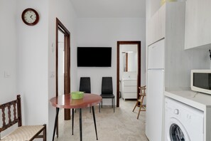 Un espace de vie compact comprenant un coin repas, un lave-linge et un téléviseur à écran plat.