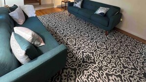 A living room with a teal sofa, patterned rug, and abstract wall art. - Hidden Gem Quiet Dead-End St Near All Casino (Montville)