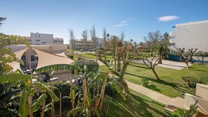 A courtyard with a pool, palm trees, and modern buildings. - 'Golden' Apartment with Shared Pool, Wi-Fi and Air Conditioning (Cabanas de Tavira)