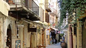 A narrow street with shops and a sign for a cardiology workshop. - Charming and serene villa with pool, lush garden, sea and mountain view (Vamos)