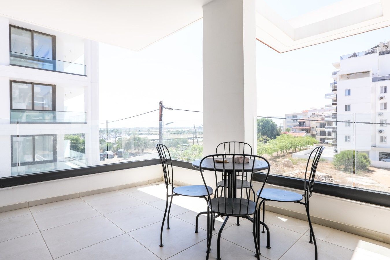 Un balcón con mesa y sillas, con vistas a una zona residencial con edificios modernos.