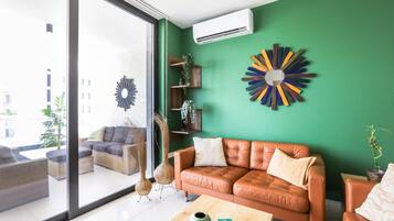 A modern living room with a green wall, a brown leather sofa, and a large window.