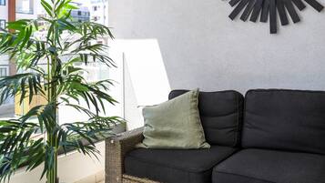 A modern living room with a black sofa, a potted plant, and a wall-mounted mirror.