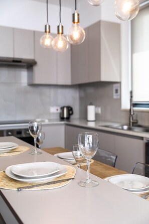 A modern kitchen with a dining area set for a meal. - Beachcomber 2-Bedroom Apartment in Larnaca (Cyprus - Larnaca)