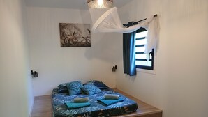 Un dormitorio pequeño con una cama, un cuadro en la pared, una ventana con cortinas y una lámpara en el techo.