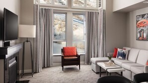 Une chambre d’hôtel moderne équipée d’un canapé, d’un fauteuil et d’un téléviseur à écran plat.