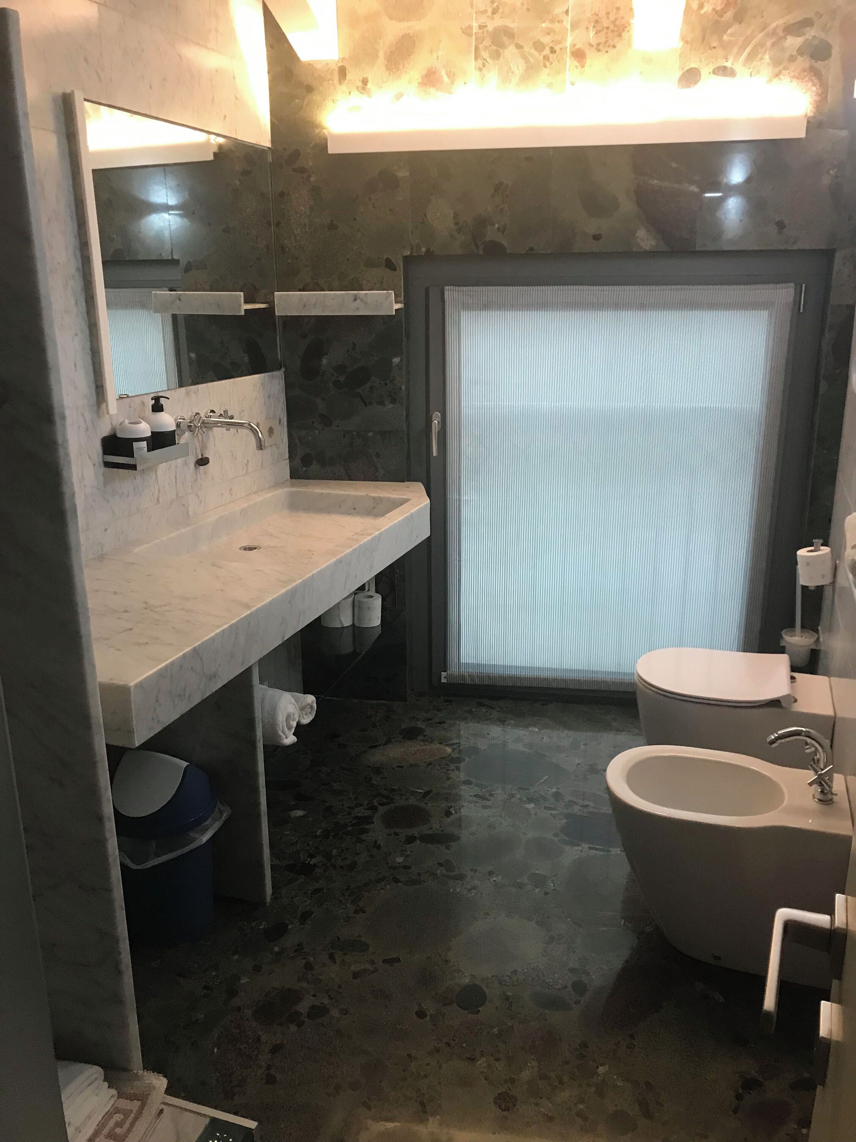 Une salle de bain moderne avec un meuble-lavabo en marbre, une baignoire sur pieds et des toilettes.