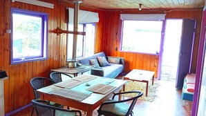 L’intérieur d’un chalet en bois comprend une table à manger, des chaises, un canapé et une petite table.