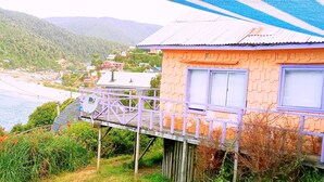 Une maison dotée d’un balcon donnant sur une rivière et des montagnes.