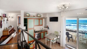 Een keuken met uitzicht op zee, een eethoek met stoelen en een trap.