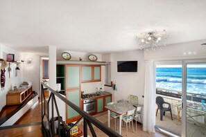 Una cocina con vista al océano, un comedor con sillas y una escalera.