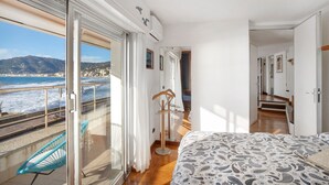 Een slaapkamer met een bed, een stoel, een kledingkast en uitzicht op zee.