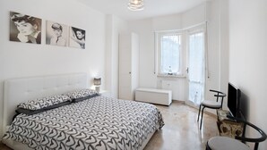 A bedroom with a bed, a chair, a television, and artwork on the wall.