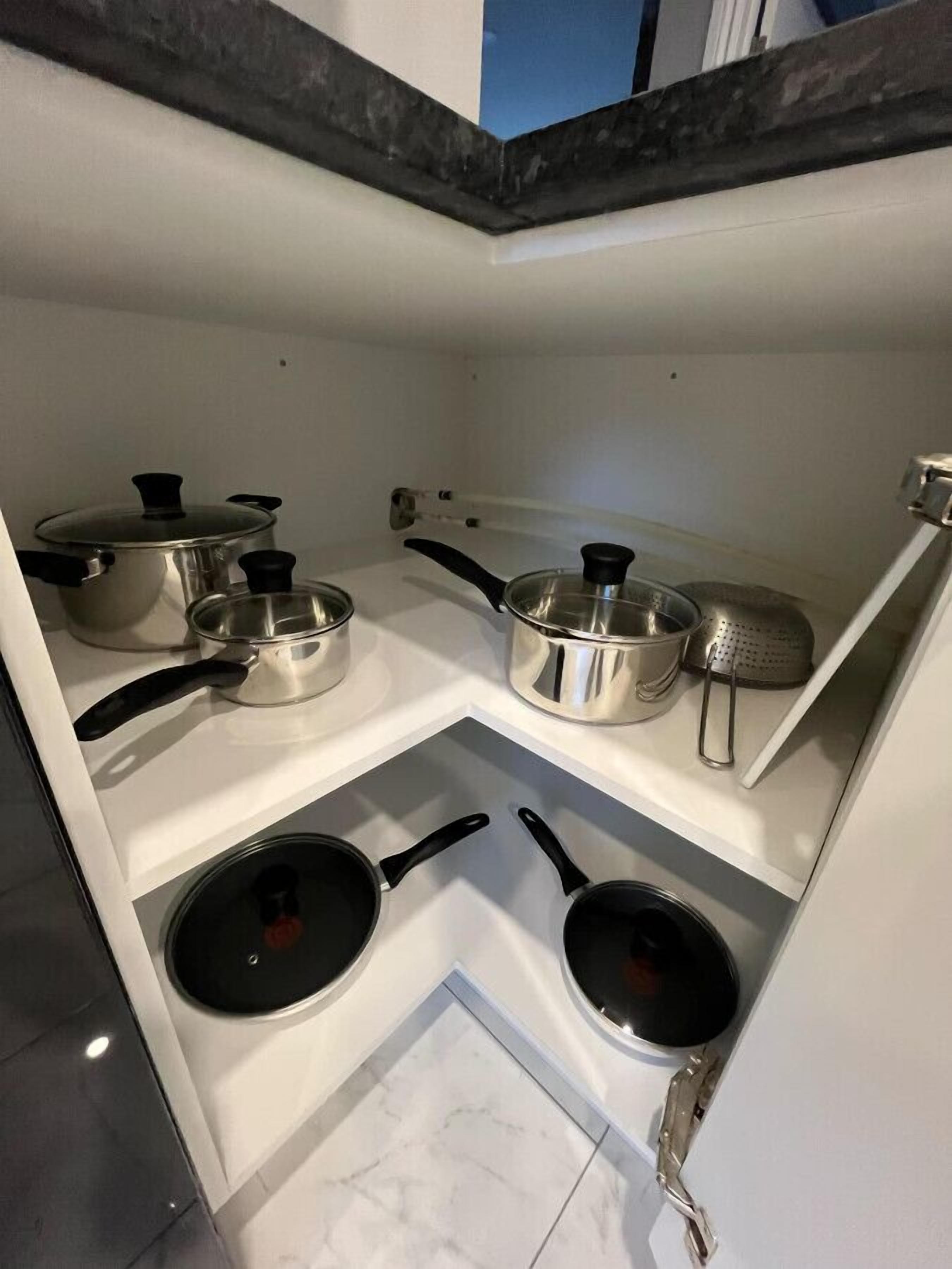 A compact kitchen with white cabinets, a stove, and various cooking utensils.