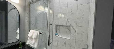 A modern bathroom with a glass-enclosed shower, a bathtub, and a vanity with a mirror and sink.