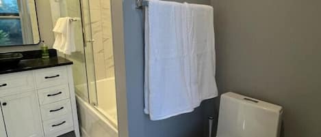 Une salle de bain moderne avec une douche à parois de verre, des toilettes blanches et un meuble-lavabo avec un miroir.
