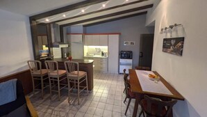 Un ambiente compatto con angolo ristoro, cucina e una piccola zona salotto.