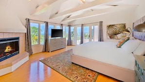 A spacious bedroom with a large bed, a fireplace, a television, and a view of the outdoors. - Last Minute Deals/A/C/Hot Tub/Great Family Home (La Jolla)