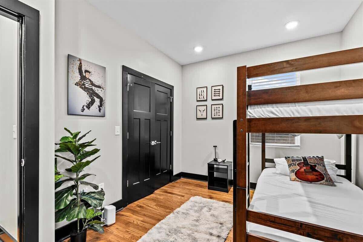Ein Schlafzimmer mit Etagenbett, Blumentopf, kleinem Schreibtisch und gerahmten Bildern an der Wand.