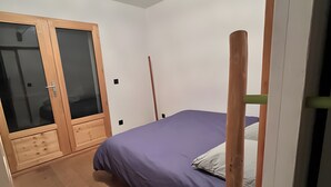 A bedroom with a bed, a wardrobe, and a hanging light fixture. - Apartment 'Au Soleil' with Mountain View, Private Garden and Wi-Fi (seez)