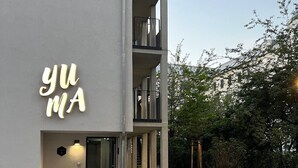 Een modern gebouw met een 'YUM'-bord, een overdekte ingang en een verhard gebied met een brandkraan.