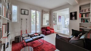 A modern living room with a red rug, a bookshelf, a red armchair, and a large mirror. - Italianway - Venini 16 (Milan)