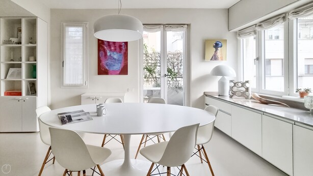 A modern kitchen with a round dining table, white chairs, and a large window with a view of greenery. - Italianway - Venini 16 (Milan)