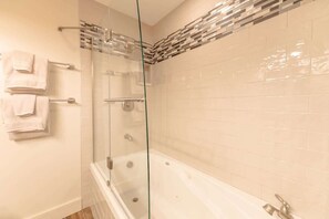 Ein Badezimmer mit einer Duschkabine, einer Badewanne und einer gefliesten Wand.
