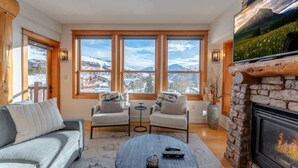 Una sala de estar acogedora con chimenea, ventanas amplias, un sofá, dos sillones y una mesa de centro.