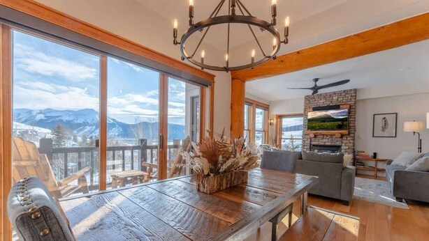 Un salón amplio con una mesa de comedor de madera, un candelabro y una chimenea.