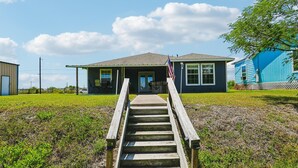 A house with a porch, a flag, and a wooden staircase leading to the entrance.