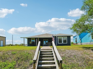 A house with a porch, a flag, and a wooden staircase leading to the entrance.