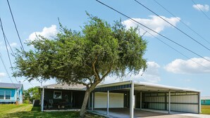 A residential property with a garage, a covered outdoor area, and a tree.