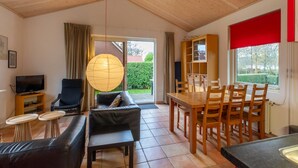 A living room with a sofa, TV, and a dining area with a table and chairs. - Holiday Home Near Beach (Oostkapelle)