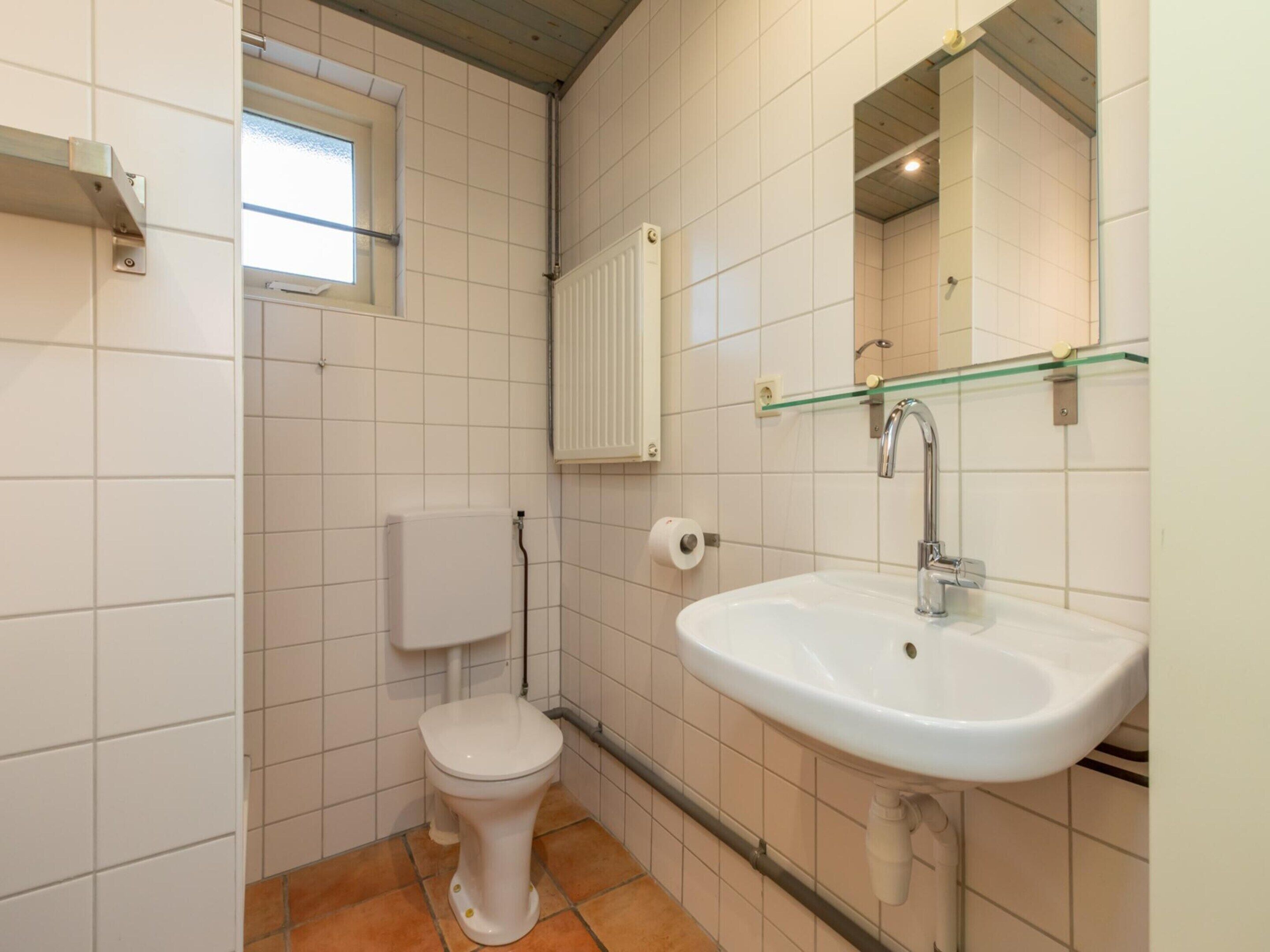 Une petite salle de bain avec des toilettes, un lavabo et une fenêtre.