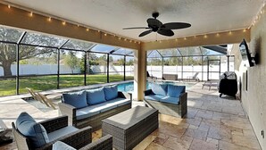 An outdoor patio with wicker furniture, a ceiling fan, and a view of a backyard swimming pool.