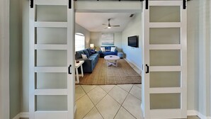 A spacious living area with a large sliding door, a sofa set, a coffee table, and a television.