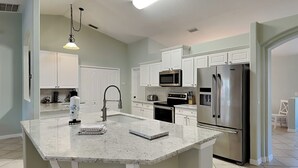 A modern kitchen with white cabinets, stainless steel appliances, and a large island.