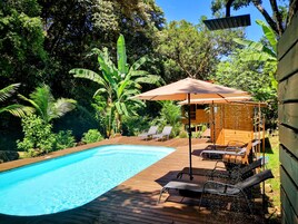 Una piscina al aire libre, sombrillas, tumbonas