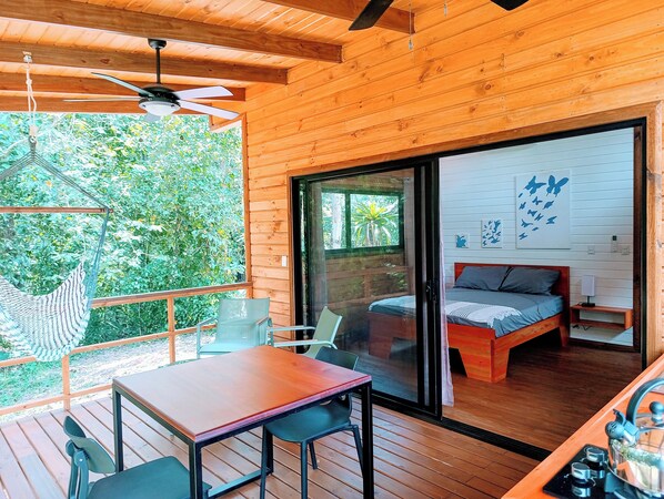 A wooden cabin with a balcony, a bed with a view, and a dining area. - Thoas Lodge (Ciudad Cortés)