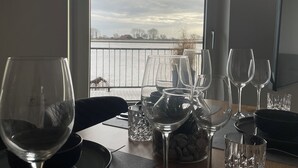 Ein Esstisch mit Weingläsern und Blick auf einen See durch ein Fenster.