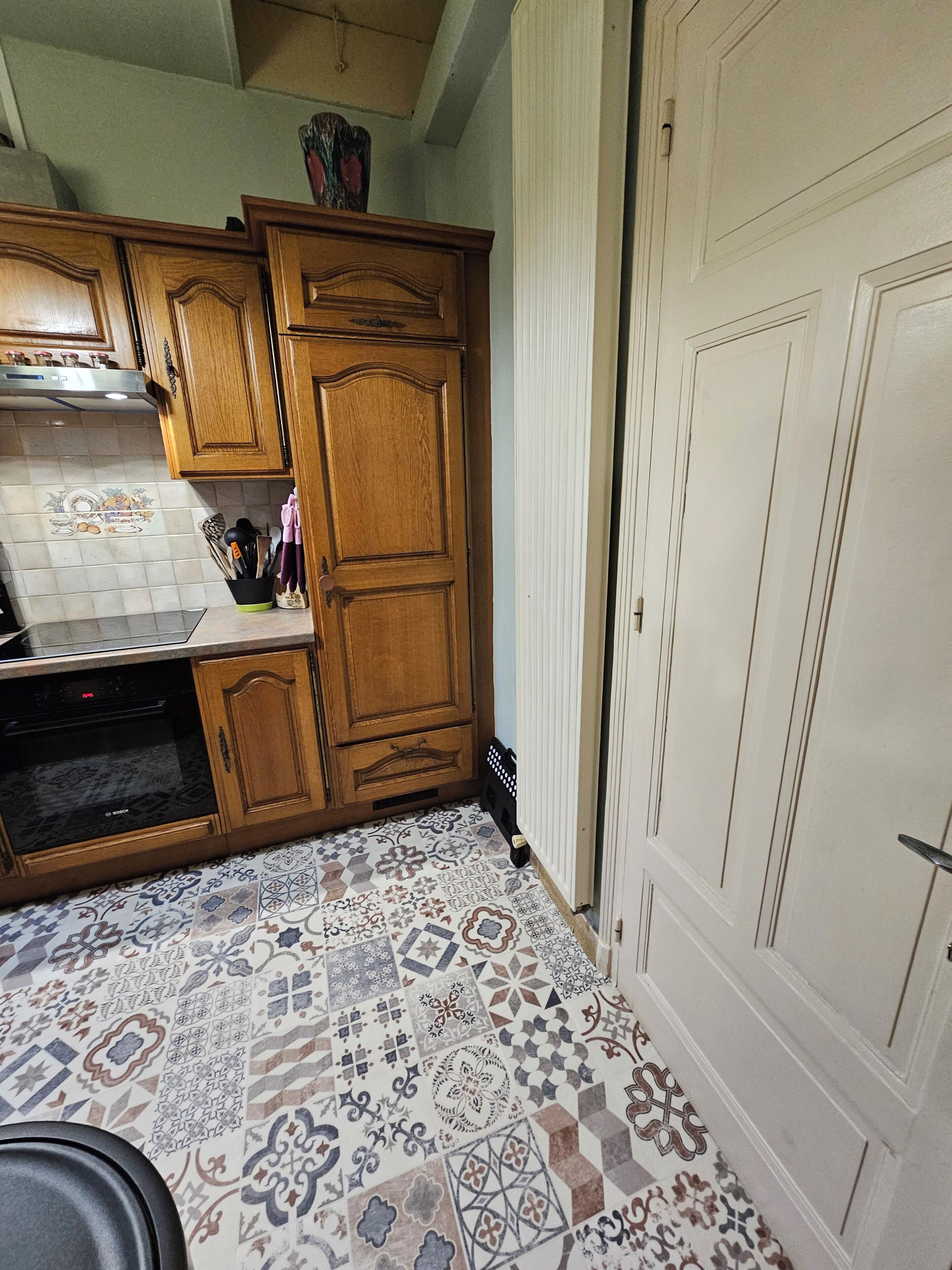 A kitchen with wooden cabinets, a Bosch dishwasher, and a patterned tile floor.