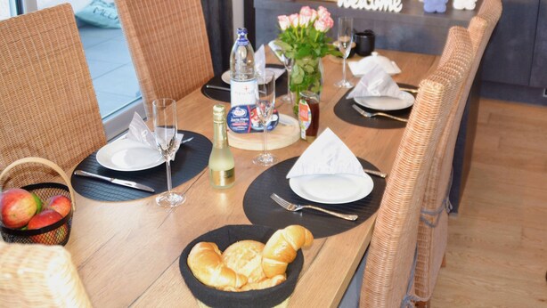 A dining table set with plates, cutlery, glasses, and a basket of apples. - * * * * * * Penthouse Meeresleuchten Duhner Entrée 19 (Cuxhaven)