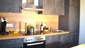 A modern kitchen with dark cabinets, stainless steel appliances, and a wooden countertop. - * * * * * * Penthouse Meeresleuchten Duhner Entrée 19 (Cuxhaven)